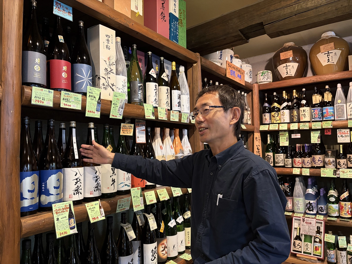 商品を手に取り、おすすめのお酒を紹介する吟酒館たからやの店主